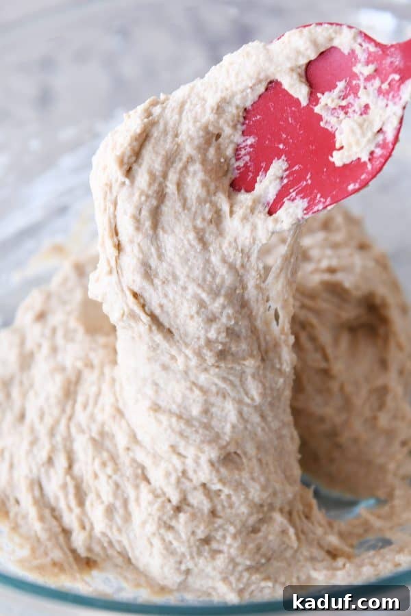 Wet english muffin dough in glass bowl.