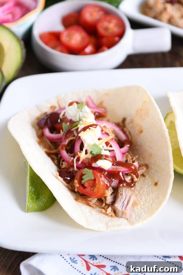 Tender BBQ Pork Tacos Instant Pot Slow Cooker Friendly 2 A delectable Instant Pot BBQ pork taco, generously filled with tender pulled pork, vibrant pickled onions, and drizzled with a rich BBQ sauce, all nestled in a soft tortilla.