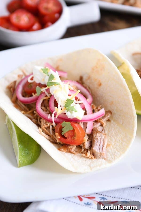 Tender BBQ Pork Tacos Instant Pot Slow Cooker Friendly 7 A perfectly assembled Instant Pot BBQ pork taco, adorned with vibrant pickled onions and a generous serving of tender, shredded pork, ready to be devoured.