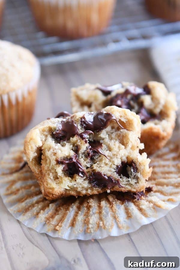 Irresistible Banana Muffins 14 A chocolate chip banana muffin, unwrapped and split in half, showcasing its moist texture and melted chocolate.