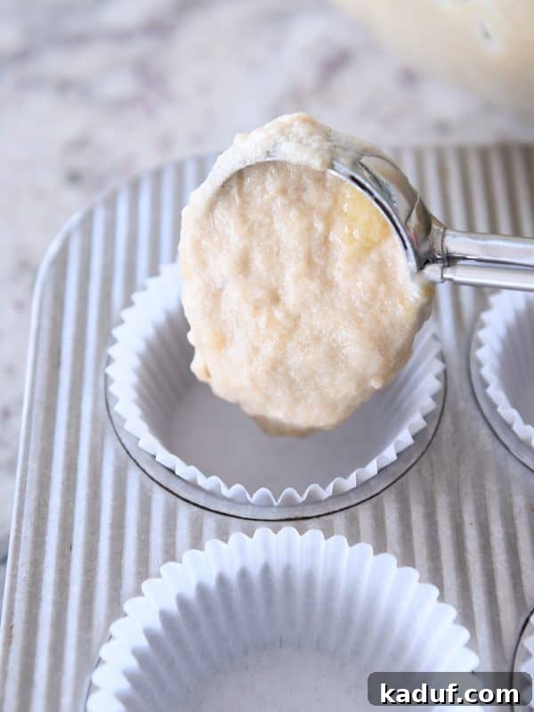 Irresistible Banana Muffins 9 Using a cookie scoop to drop banana muffin batter into paper-lined muffin tins.