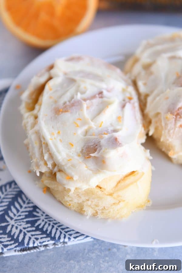 Sun-Kissed Orange Swirl Rolls 15 Homemade orange sweet roll on white plate.