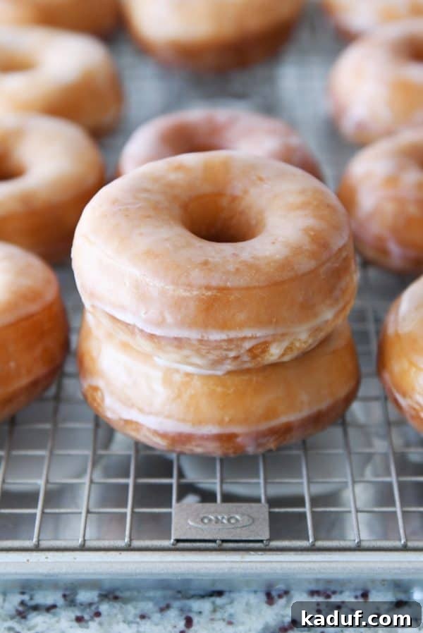 Melt-in-Your-Mouth Homemade Glazed Donuts 24 Stacked homemade glazed donuts on a wire rack, glistening with sweet glaze.