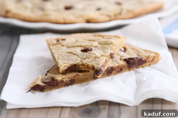 Effortless 12-Inch Monster Chocolate Chip Cookie 4 Artfully arranged slices of a giant chocolate chip cookie on a white napkin, showcasing its enticing texture and generous chocolate chunks.