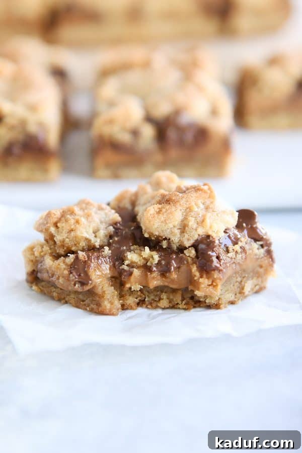 A delectable caramel peanut butter s'mores cookie bar with a bite taken out, revealing its soft, chewy interior.