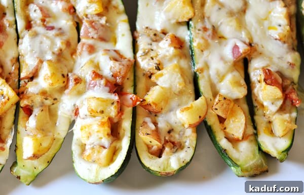 Savory Zucchini Boats 3 Rows of perfectly baked stuffed zucchini boats lined up on a white platter, ready to be served.