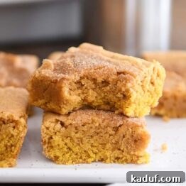two pumpkin snickerdoodle bars stacked on white tray with bite taken out of top bar