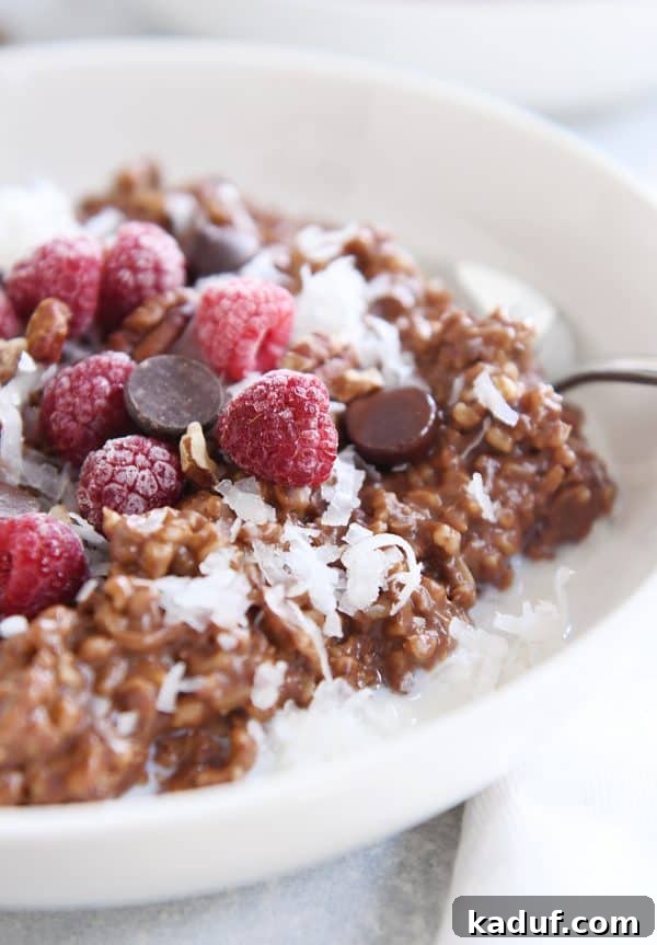 Chocolate Lover's Instant Pot Steel Cut Oats 3 Instant pot chocolate steel cut oats in white bowl with chocolate chips and frozen raspberries.