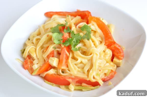 Creamy Red Coconut Noodle Curry 3 White bowl with cooked pasta and strips of red bell pepper.