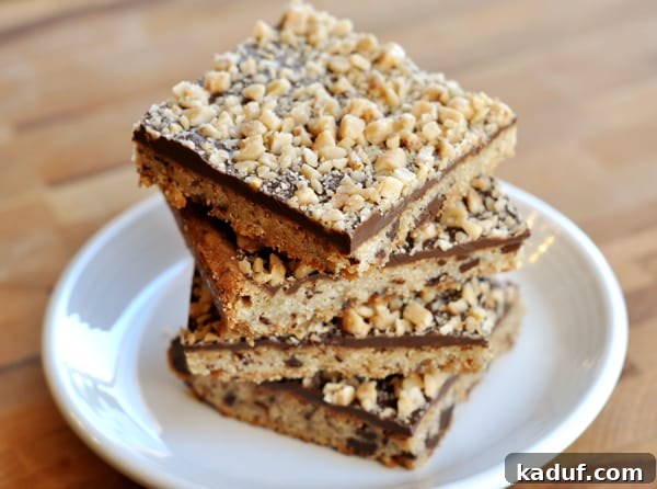 Golden Toffee Chocolate Shortbread 3 A tempting stack of multiple chocolate toffee shortbread bars on a white plate, highlighting their distinct layers and inviting texture.