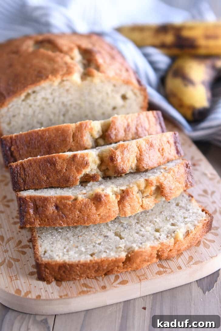 Luscious Buttermilk Banana Bread 2 Four slices of buttermilk banana bread on wood cutting board, showcasing its light, fluffy texture and golden crust.