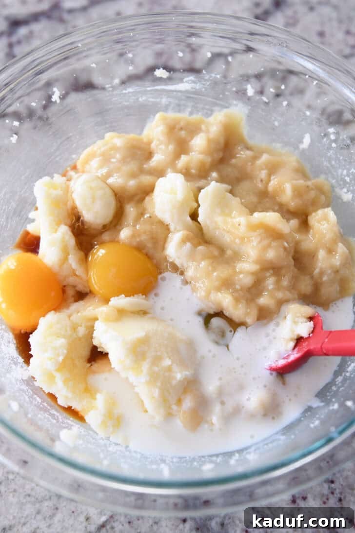 Luscious Buttermilk Banana Bread 4 Top down view of banana bread ingredients in a glass bowl, including mashed bananas and wet ingredients.