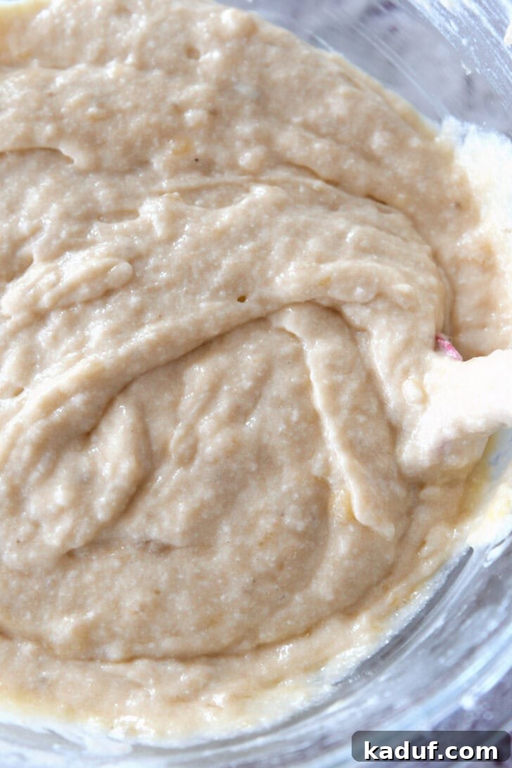 Luscious Buttermilk Banana Bread 6 Top down view of banana bread batter being mixed in a glass bowl, showing a smooth consistency.