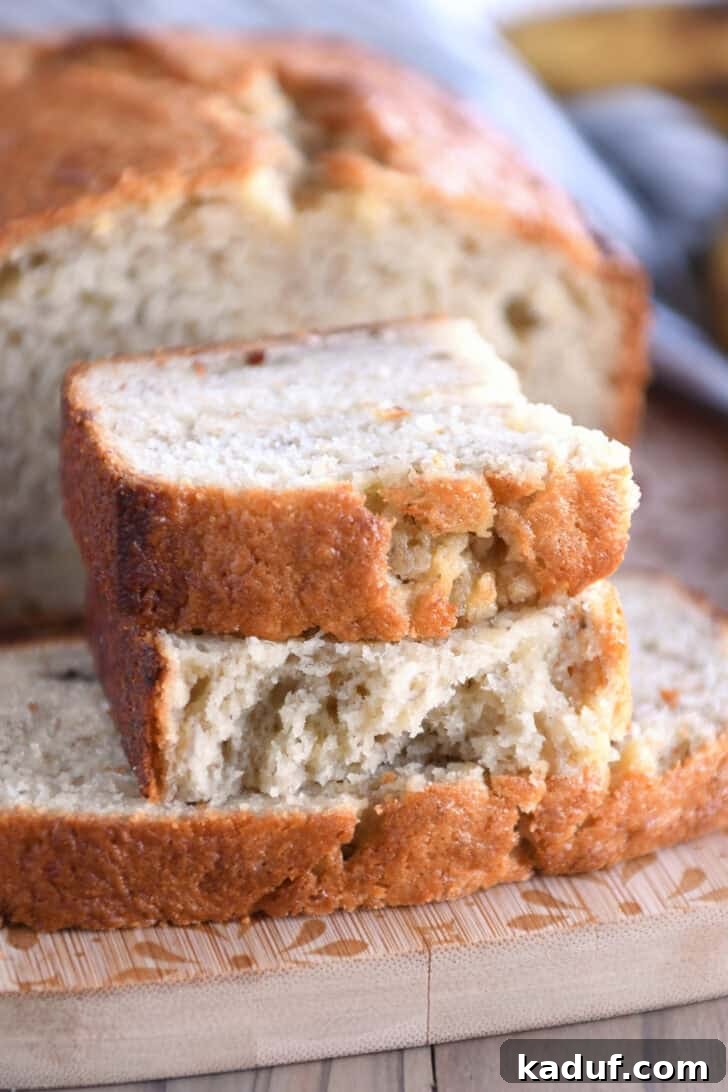 Luscious Buttermilk Banana Bread 9 Two half slices of perfectly baked banana bread arranged on a rustic wood cutting board.