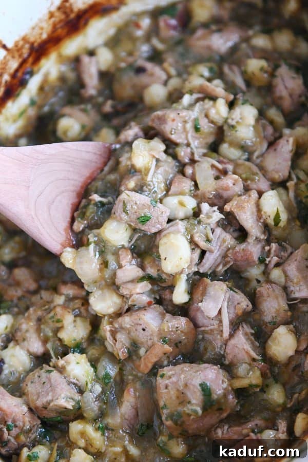 Easy Slow Cooker Posole 6 Scooping slow cooker posole with wooden spoon.