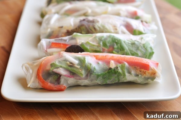 How to Make Fresh Vietnamese Spring Rolls 3 Spring rolls lined up in a row on a white platter, ready to be served.