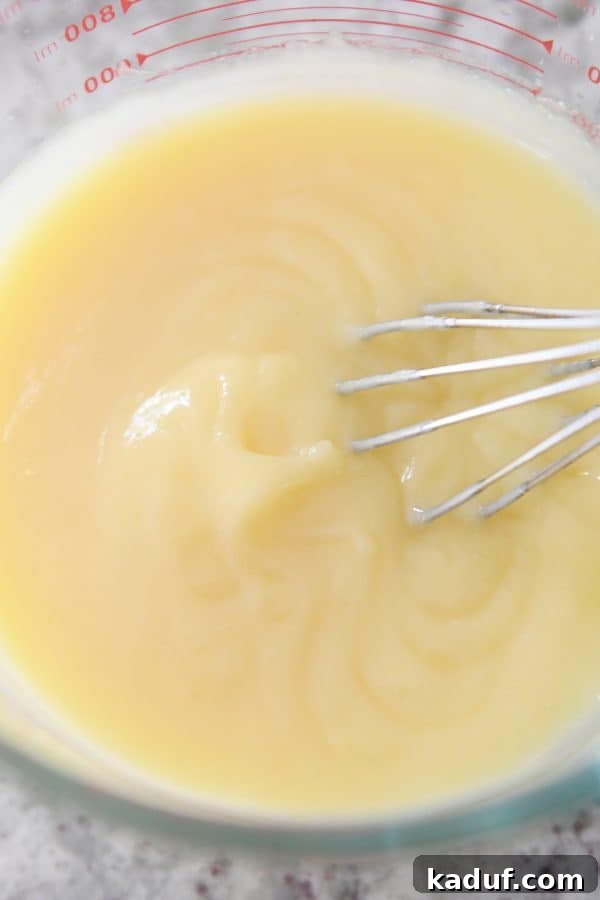 Easy Instant Pot Lemon Curd 7 A whisk is gently lifted from a bowl of perfectly smooth and creamy Instant Pot lemon curd, ready for chilling.