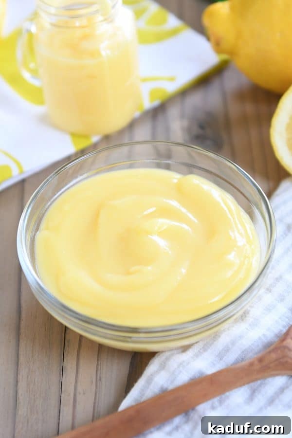 Easy Instant Pot Lemon Curd 8 A clear glass bowl brimming with golden lemon curd, resting on a striped napkin, ready for serving or storage.