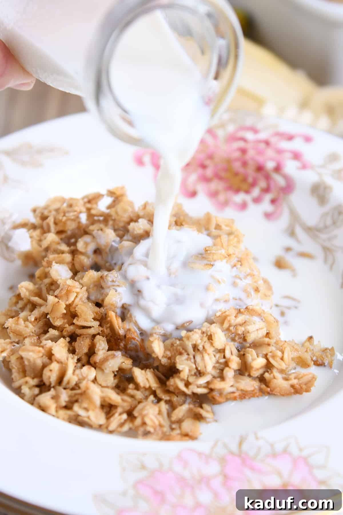 Effortless Amish Overnight Baked Oats 7 A stream of fresh milk gracefully pours into a bowl of warm, easy Amish baked oatmeal, ready to be enjoyed with its comforting, creamy texture.