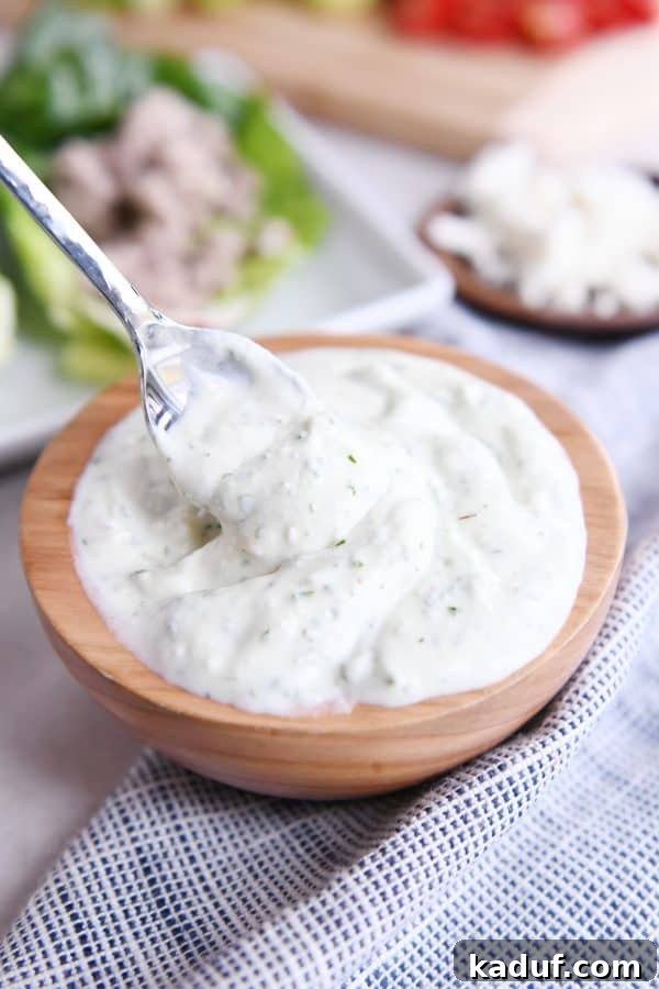 Zesty Greek Lettuce Boats 5 A wooden bowl filled with the luscious mint feta dressing, with a spoon resting inside, inviting you to taste.