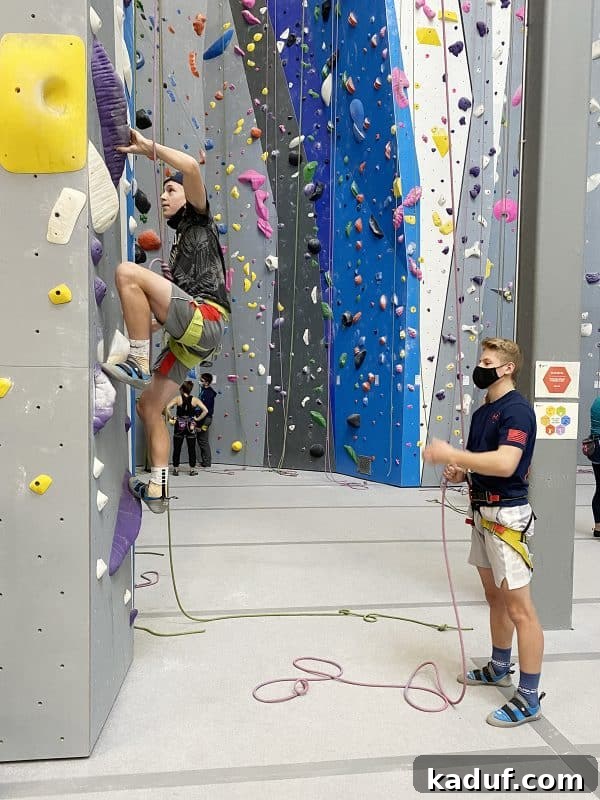 Friday Musings 7 two teenage boys, one actively rock climbing on a tall indoor wall, the other belaying below