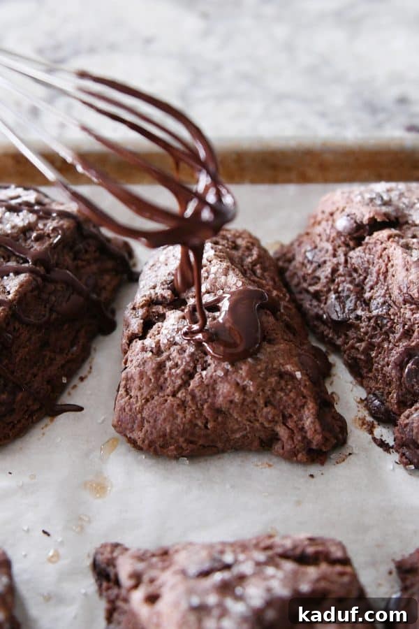 Divine Triple Chocolate Scones 9 Rich chocolate glaze being artfully drizzled from a whisk onto warm chocolate scones, creating a beautiful finish.