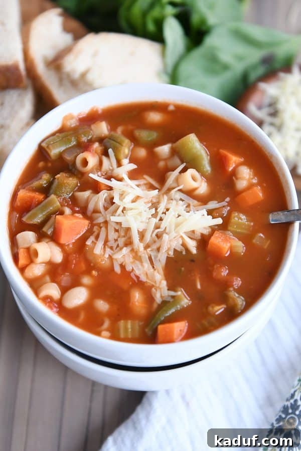 Rustic Italian Minestrone 2 Minestrone soup in two stacked white bowls with parmesan cheese, garnished with fresh herbs.