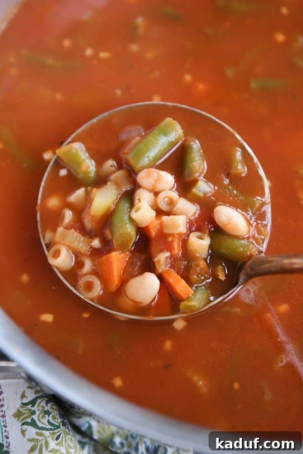 Rustic Italian Minestrone 6 A close-up of a ladle dipping into a pot of minestrone soup, showing a rich broth and colorful vegetables.