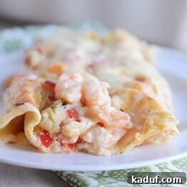 Creamy Shrimp Enchiladas 5 Closeup of two shrimp enchiladas on white plate.