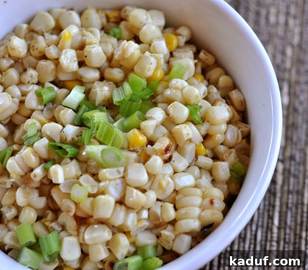 Fire-Kissed Corn Medley 2 White bowl with vibrant grilled corn kernels and freshly chopped green onions, showcasing the salad's fresh appeal.