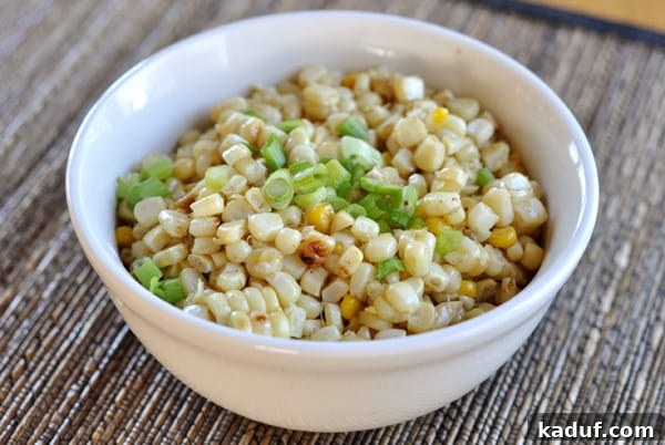 Fire-Kissed Corn Medley 3 A crisp white bowl showcasing grilled corn kernels beautifully topped with bright green onion slices, ready to be enjoyed.