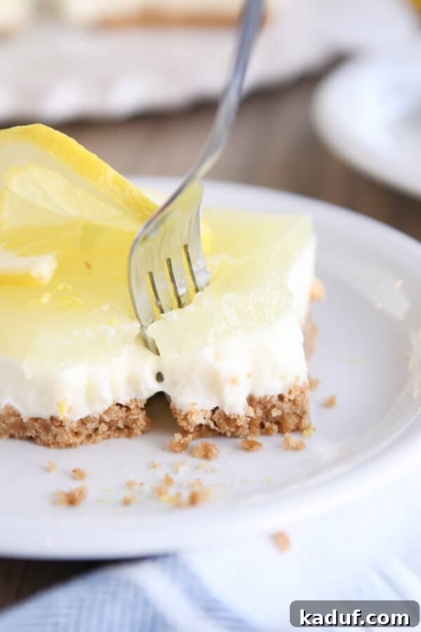 Zesty Lemon White Chocolate Squares 3 Pulling a piece of lemon cheesecake bar away with fork, showcasing the layered texture.
