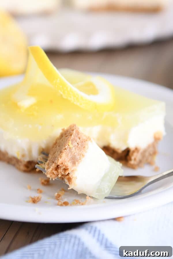 Zesty Lemon White Chocolate Squares 9 Square of lemon white chocolate cream bars on a white plate with a bite taken on a fork, showing its refreshing quality.