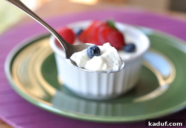 Aspen Gold Crème 3 Small white ramekin with cream dessert topped with fresh berries, and a spoon taking a bite out.