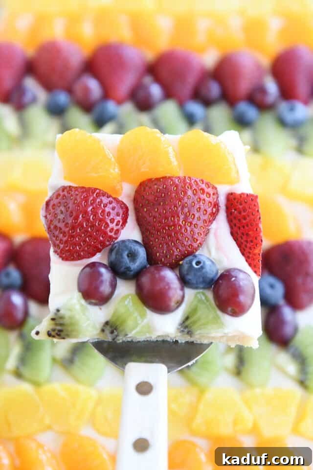 The Perfected Fruit Pizza 10 Square of fruit pizza with mandarin oranges, strawberries, blueberries, red grapes and kiwi above sheet pan fruit pizza.