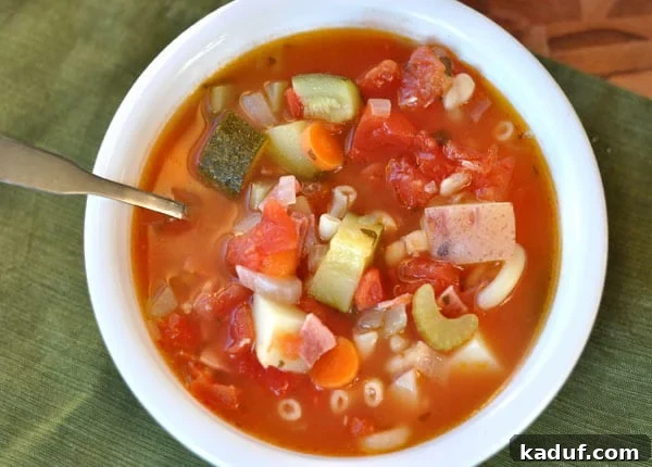 Autumn's Bounty Minestrone 3 Top view of a white bowl full of minestrone soup filled with pasta and chopped vegetables.
