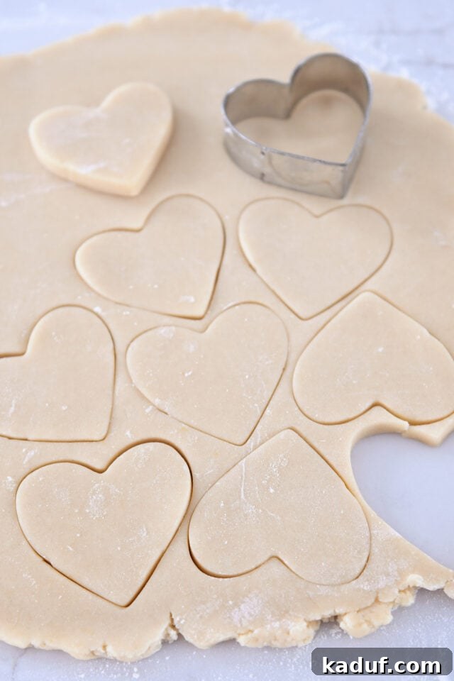The Ultimate Cutout Sugar Cookie Recipe 7 Sheet of sugar cookie dough with heart shaped cookies cutout.