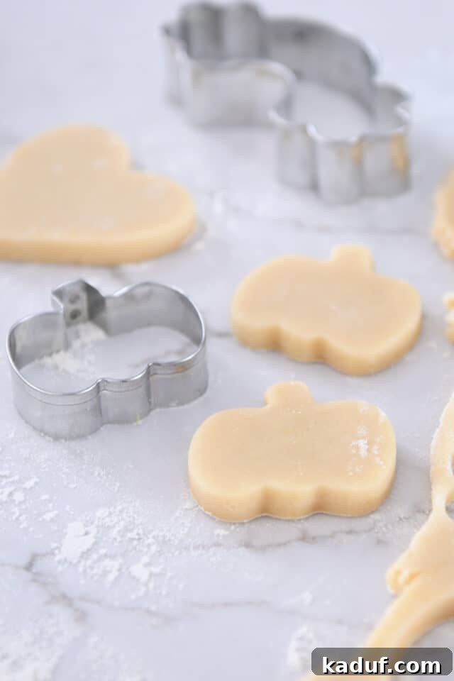 The Ultimate Cutout Sugar Cookie Recipe 8 Unbaked pumpkin shaped sugar cookies on counter.