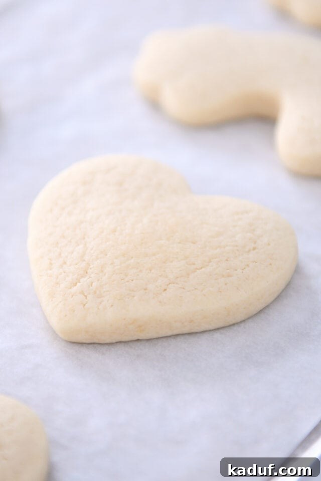 The Ultimate Cutout Sugar Cookie Recipe 9 Heart shaped sugar cookie on parchment lined baking pan.