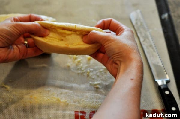 Orange Glazed Sweet Rolls 9 Hands stretching an uncooked sweet roll into an oblong shape.