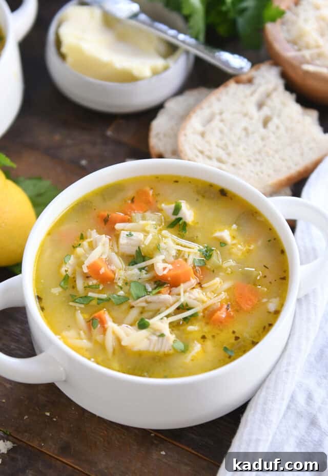 Bright Lemon Chicken Orzo Soup 2 Hearty Lemon Chicken Orzo Soup in a white bowl with handles, served with slices of crusty bread and butter, ready to be enjoyed.