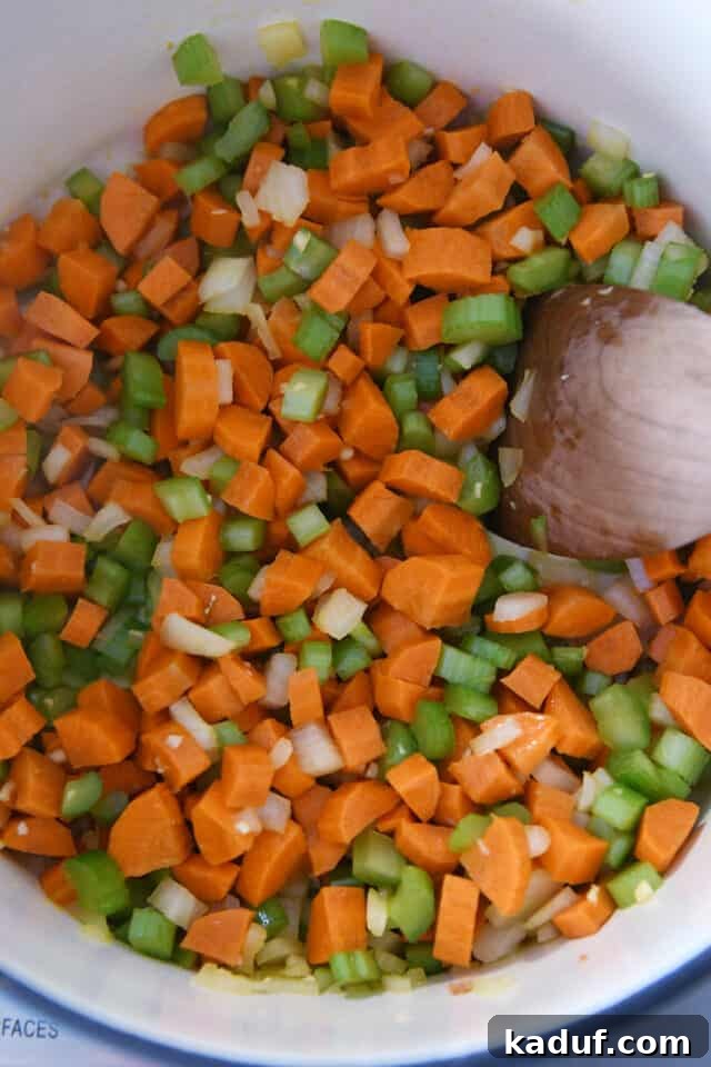 Bright Lemon Chicken Orzo Soup 3 A cast iron pot showing diced carrots, onions, and celery gently sauteing to form the flavorful base of the lemon chicken orzo soup.