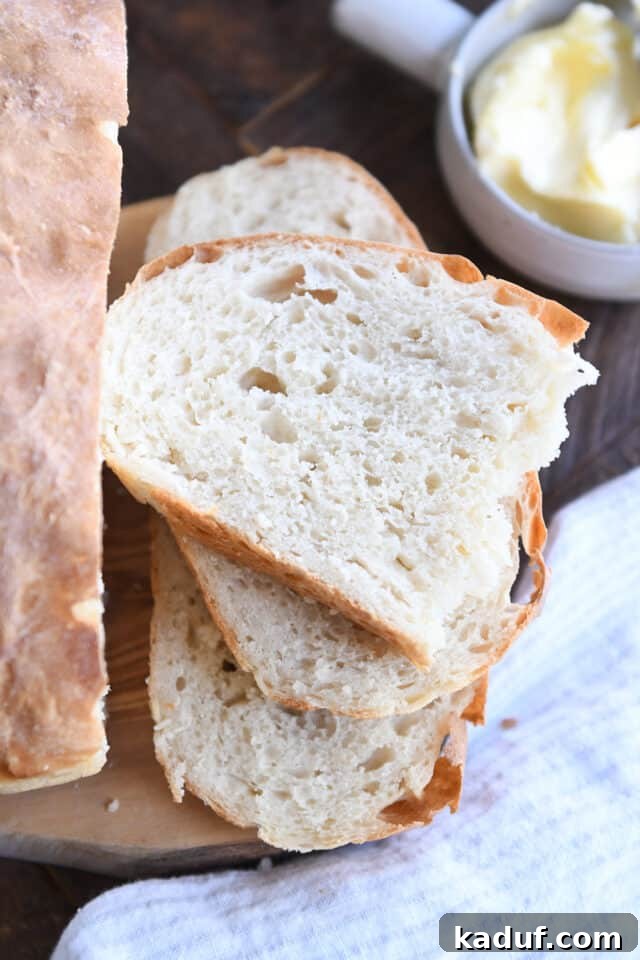Pratik Yoğurmasız Köy Ekmeği 11 Beautifully cut slices of the easy no-knead peasant bread are neatly stacked, showcasing the fluffy interior and golden crust.