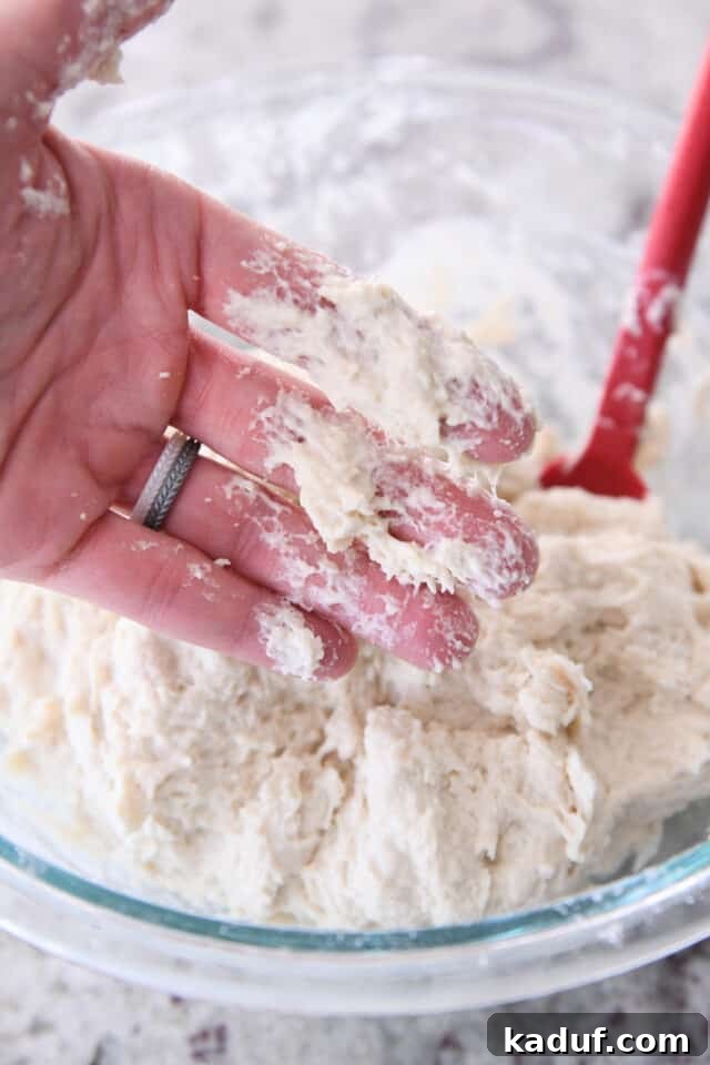 Pratik Yoğurmasız Köy Ekmeği 5 A close-up view of sticky dough residue clinging to fingertips, demonstrating the high hydration of the no-knead peasant bread dough.
