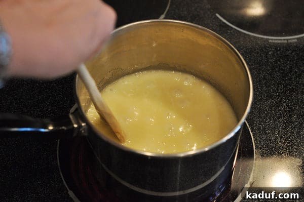 Golden Almond Toffee 10 Melted butter bubbling in a saucepan with a wooden spoon stirring it, indicating the start of the toffee cooking process.