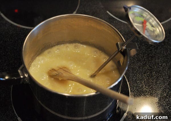 Golden Almond Toffee 11 Melted butter in a saucepan with a wooden spoon and candy thermometer clipped to the side of the pan, ready for precise temperature monitoring.