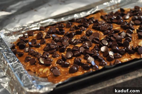 Golden Almond Toffee 19 Chocolate chip covered almond roca on a tinfoil lined cookie sheet, showing the melted and smooth chocolate layer.