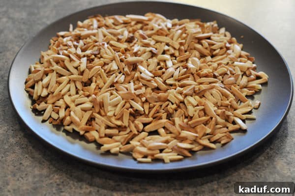 Golden Almond Toffee 6 Dark plate full of perfectly toasted almond slices, prepped for the almond roca recipe.