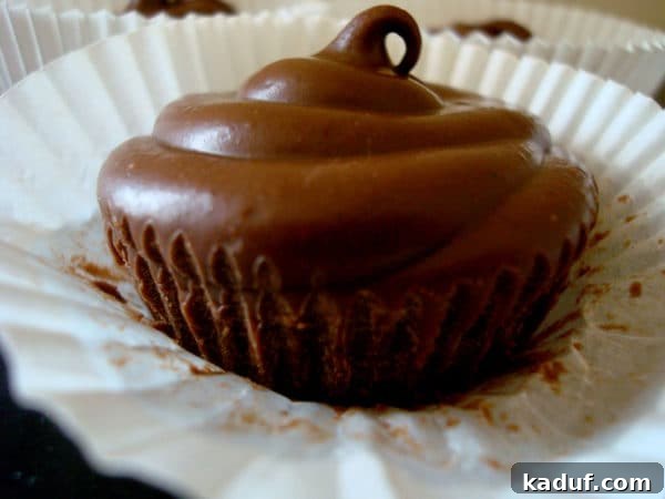Firm Peanut Butter Cups 3 A single solid chocolate peanut butter cup, unwrapped and ready for a bite, resting in a white muffin liner.