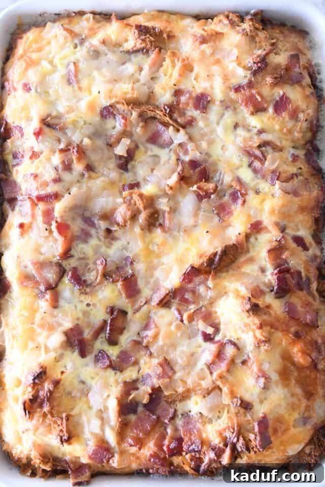 Overnight Cheesy Bacon Croissant Strata 6 Puffy, golden-brown baked croissant casserole in a white 9X13-inch pan, fresh out of the oven.